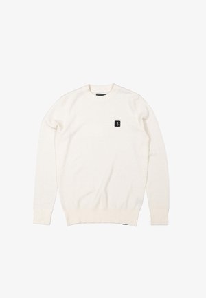 White knit sweater with a textured pattern, round neckline, and ribbed cuffs, featuring a small black logo patch on the chest.