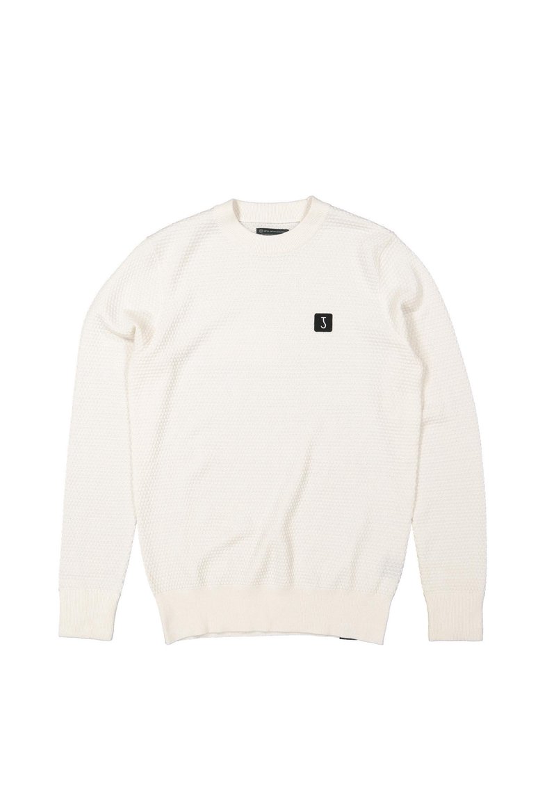 Pull en tricot blanc avec un motif texturé, col rond et poignets côtelés, arborant une petite patch logo noire sur la poitrine.