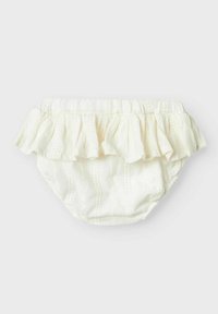 Culotte en coton blanc avec volants, texture gaufrée et taille élastique. Présente un volant décoratif à l'arrière.