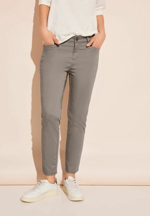 Pantalones chinos grises de corte ajustado, con bolsillos delanteros, cierre de botones y textura suave; combinados con zapatillas blancas.