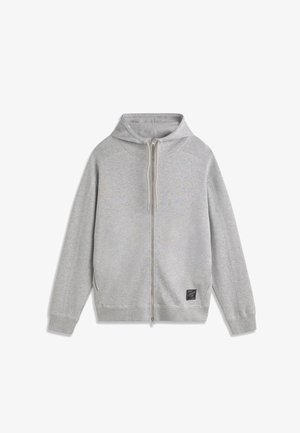 Felpa con cappuccio grigia chiara con zip integrale, coulisse, maniche lunghe, polsini a costine e una piccola toppa nera vicino all'orlo inferiore sul lato destro.