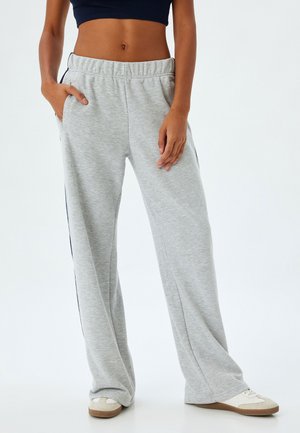 Grijze sweatpants met een relaxte pasvorm, elastische tailleband, zijzakken en contrasterende marineblauwe zijstrepen. Gemaakt van zachte, gestructureerde stof.