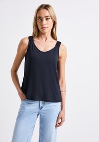 Top senza maniche di colore blu navy con scollo rotondo, dotato di spalline arricciate, realizzato in tessuto morbido. Abbinato a jeans azzurri.