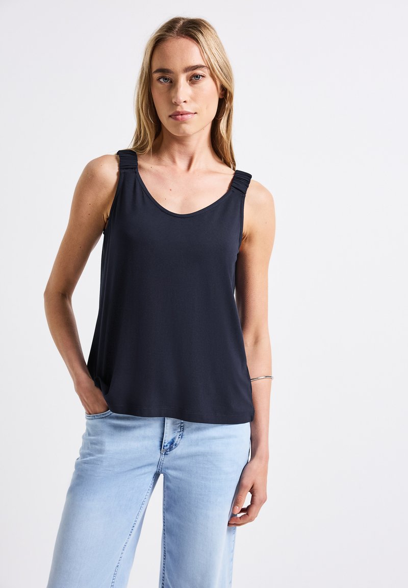 Top senza maniche di colore blu navy con scollo rotondo, dotato di spalline arricciate, realizzato in tessuto morbido. Abbinato a jeans azzurri.