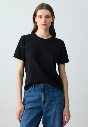 Zwarte katoenen t-shirt met korte mouwen, ronde halslijn, gecombineerd met blauwe denim high-waisted jeans. Glad textuur, casual pasvorm.