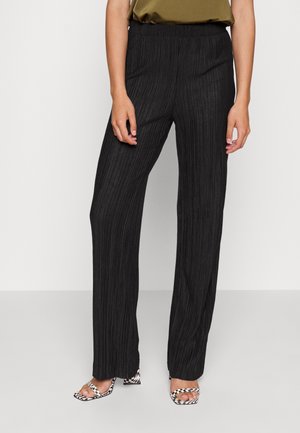 Zwarte, geplooide wijde broek met een elastische tailleband; gecombineerd met gestreepte sandalen, die een gladde textuur en een sleek design tonen.