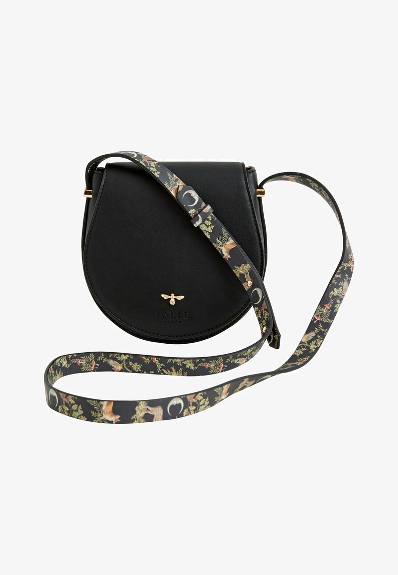 Svart läder crossbody-väska med en halvmåneform, pryds av ett blommönstrat rem och har en goldlogotyp framtill.