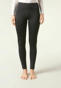 Svarta leggings med hög midja, slät textur, full längd och minimala sömmar, designade för komfort och flexibilitet.