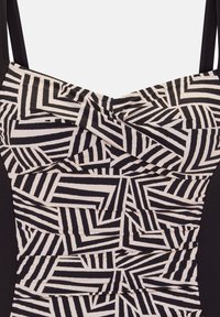 Črno-bela kopalna obleka s geometrijskim vzorcem. Narejena iz raztegljive tkanine, z nastavljivimi naramnicami in zategnjenimi detajli.