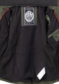 Zwarte fleece-gevoerde binnenkant van een jas met groene accenten, voorzien van een merketiket en een extra label. Eenvoudig ontwerp, praktische zakken.