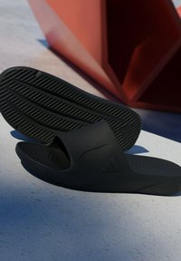 Black rubber slide sandals with an open toe design, textured insole, and patterned outsole featuring grooves for traction.
