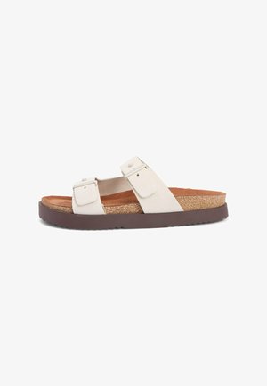 White double-strap slide sandal with adjustable buckles, cork footbed, and thick textured brown sole, shown in side view.