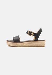 Sandalias de plataforma de piel negra con suela de yute trenzado, detalle de hebilla en la correa y un acabado suave en la planta.