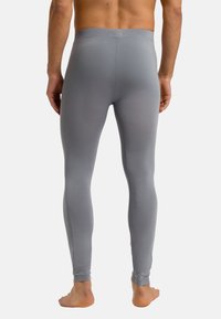 Leggings grises hechos de una tela lisa y elástica con un diseño ajustado, que se estrecha en los tobillos, y con una suave cinturilla elástica.
