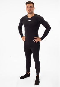 Schwarzes, athletisches Basisschicht-Set mit langen Ärmeln und Leggings. Hergestellt aus glattem, elastischem Stoff. Mit einem Logo auf der Brust.
