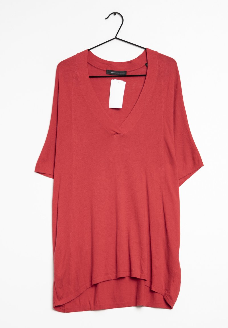 Red short-sleeve v-neck top made of lightweight fabric, featuring a loose, relaxed fit and a curved hem, with a hanging tag attached.