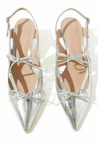 Srebrne metalik balerinke s oštrim vrhom, otvorenim stranama i ukrštenim vezicama sprijeda. Glatka tekstura s sjajnom završnom obradom.