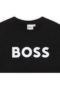 T-shirt preta com decote redondo e logótipo "BOSS" em branco destacado no peito. Tecido macio com textura suave.
