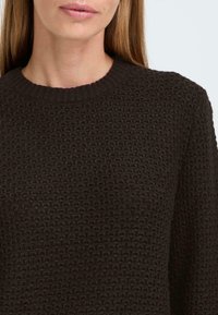 Dark brown knitted sweater featuring a textured, honeycomb pattern and a ribbed crew neckline. The fabric appears soft and cozy.