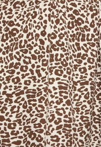 Tecido com padrão de leopardo castanho sobre um fundo de creme claro, apresentando manchas de formas variadas em uma textura suave. Adequado para vestuário ou acessórios.