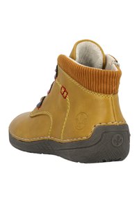 Bottine en cuir beige avec un col orange côtelé, des lacets rouges et bleus, et une semelle grise texturée présentant un logo au talon.