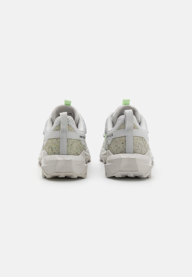 Graue Turnschuhe mit einer strukturierten, gesprenkelten grünlich-gelben Ferse, ausgestattet mit einer gepolsterten Sohle und einem hellgrünen Zugtab hinten.