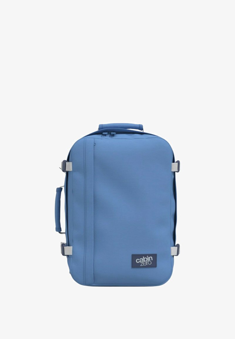 Zaino blu realizzato in un materiale liscio e resistente, forma rettangolare, con maniglia superiore e cinghia laterale, dotato di logo sulla parte anteriore.