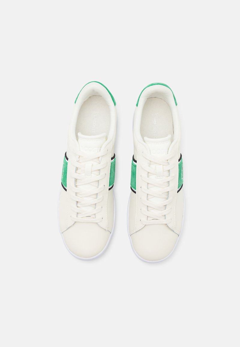 Białe sneakersy z zielonymi zamszowymi akcentami i czarnymi detalami. Okrągły czubek, sznurowany fason, teksturowany materiał i logo na języku.