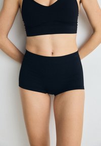 Black ribbed cotton bralette and matching high-waisted shorts. The fabric is soft with a smooth texture and a fitted silhouette.