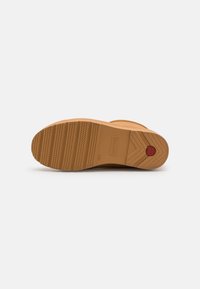 Brauner Gummistiefelsole mit geriffelter Textur und ausgeprägtem Profilmuster. Verfügt über ein zentrales Logo und einen roten kreisförmigen Akzent.
