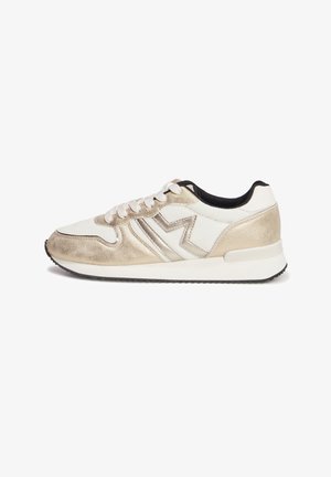 Zapatillas con una parte superior de ante dorado claro, detalles en negro y una entresuela blanca texturizada. Presenta un diseño decorativo en zigzag en el lateral.