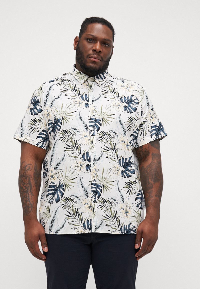 Camisa de botones de manga corta con una base blanca y un estampado de hojas tropicales en azul y verde, junto con acentos florales. Tejido de algodón, corte relajado.