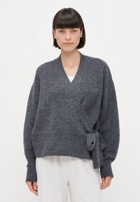 Grau umwickelter Cardiagan aus einem weichen Strickstoff, mit einem Bindegürtel in der Taille, langen Ärmeln und einer entspannten Silhouette.