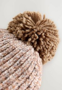 Strickmütze aus weichem, strukturiertem Garn, mit einem mehrfarbigen Muster in Beige und Pink, die mit einem fusseligen braunen Pompon verziert ist.