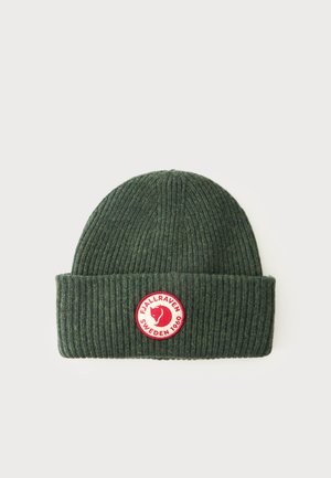 Ciemnozielona prążkowana dziana czapka z wywiniętym mankietem, z okrągłą czerwoną i białą naszywką z logo Fjallraven Sweden 1960 z przodu.