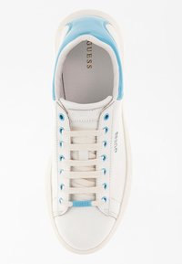 Bílé kožené tenisky s modrými akcenty, kulatou špičkou a plochými tkaničkami. Obsahují modré očky a logo "GUESS" na jazyku. Hladký povrch.