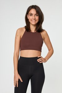 Brahk barvna kratka halter bluza iz raztegljive tkanine, v kombinaciji z visokimi črnimi legicami. Vidna je gladka tekstura in minimalni šivi.