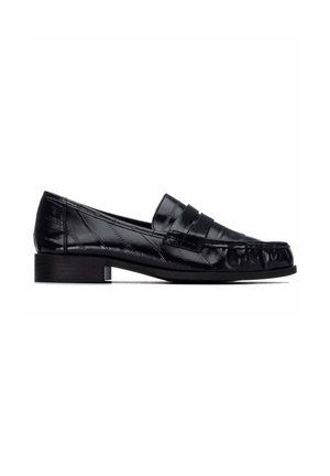 Mocasín de cuero negro con tacón bajo, puntera redondeada y una correa decorativa en la parte superior.