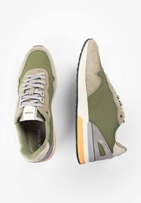 Olivově zelené tenisky s vrchní částí z semiše a textilu, šedými akcenty, šedými tkaničkami a texturovanou podešví s oranžovým detailem.