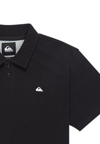 Zwarte polo met een drieknoopsluiting, gemaakt van textuurstof, met een klein wit logo op de linkerkant van de borst.