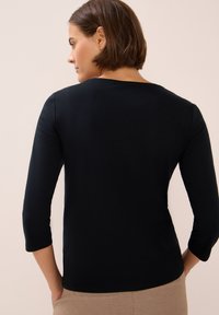 Zwarte lange mouwen top met een ronde halslijn en een getailleerd ontwerp. Glad, rekbaar materiaal, met 3/4 mouwen en een eenvoudige silhouet.