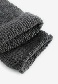 Grå strikket uldscarf med et struktureret, ribbet design. Har en tyk, rullet kant og blød, hyggelig stof.