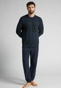 Námořnický kostkovaný svetr s dlouhými rukávy a kulatým výstřihem, kombinovaný s námořnickými tepláky. Měkký materiál, elastické manžety a ležérní střih.