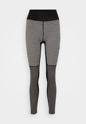 Sorte og grå stripete leggings med høy midje. Den nederste delen har et teksturert svart mønster. Materialet er elastisk og tettsittende.