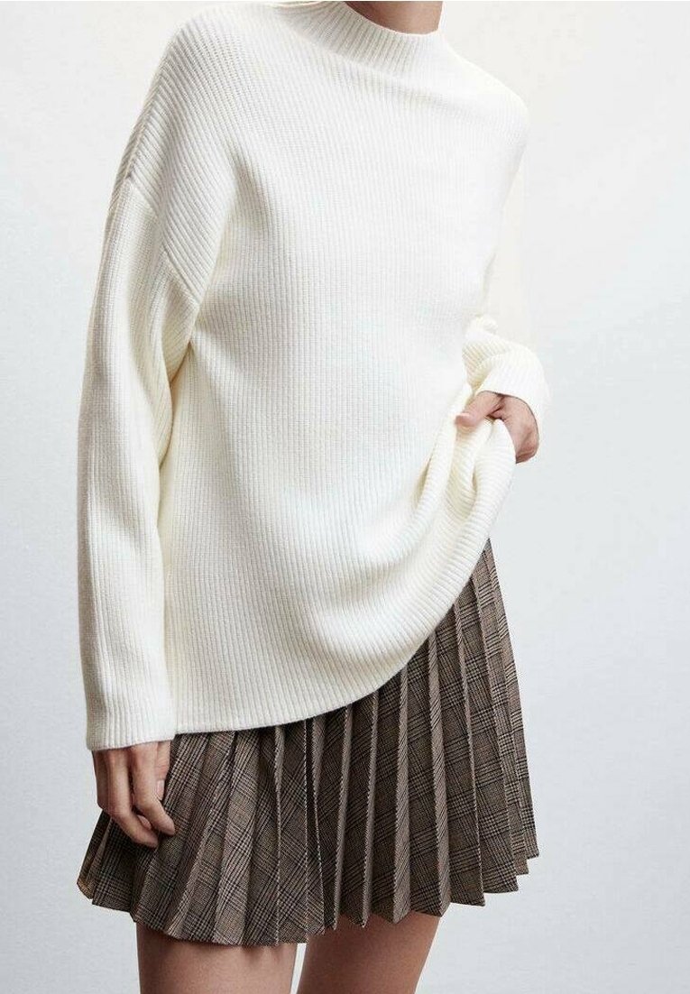 Pull blanc côtelé à col montant et manches longues, associé à une jupe plissée à carreaux marron avec des textures et plis subtils.