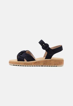 Navy suede sandals with a knotted forefoot and an ankle strap, featuring a textured cork footbed and a ridged rubber outsole.