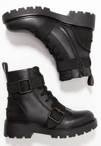 Czarne skórzane botki za kostkę o fakturowanym wykończeniu, z przodem na sznurowadła, ozdobione klamrami i solidną, bieżnikowaną podeszwą.