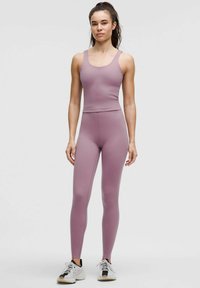 Heled lilla spordikomplekt, mis sisaldab sobivat tank topsi laia rihmaga ja kõrge vöökohaga retuuse, valmistatud siledast, venivast materjalist.