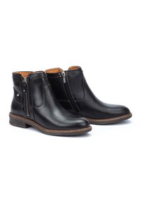 Bottines en cuir noir avec fermetures éclair sur les côtés, texture lisse, bout rond et semelle marron cousue. Intérieur doublé en matériau beige.