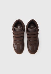 Braune High-Top-Sneaker mit drei Klettverschlussriemen, einem Obermaterial aus glattem Leder und strukturiertem Stoff sowie einer Gummisohle mit Belüftungsperforationen.